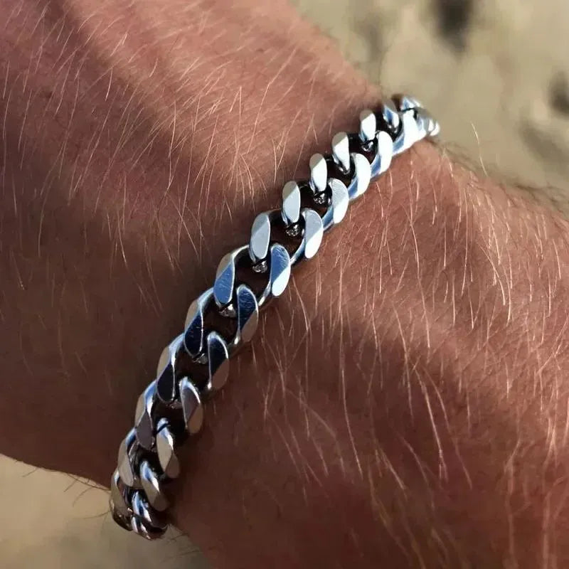 Silver Cuban chain bracelet worn on the wrist, close-up outdoors in bright sunlight.