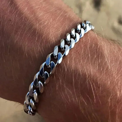Silver Cuban chain bracelet worn on the wrist, close-up outdoors in bright sunlight.