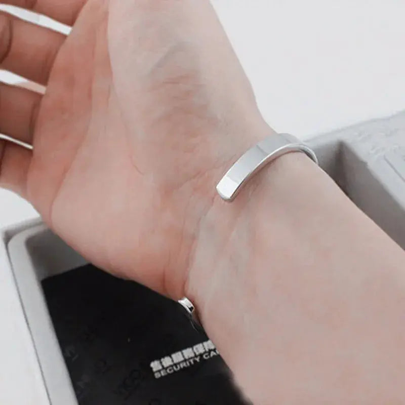 Silver stainless steel open cuff bangle worn on wrist