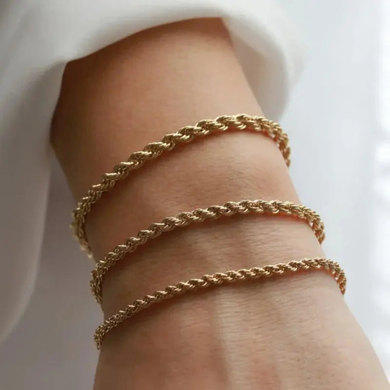 Three gold twisted rope chain bracelets stacked on wrist