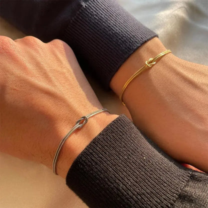 Gold and silver stainless steel knot chain bracelets worn as a couple set