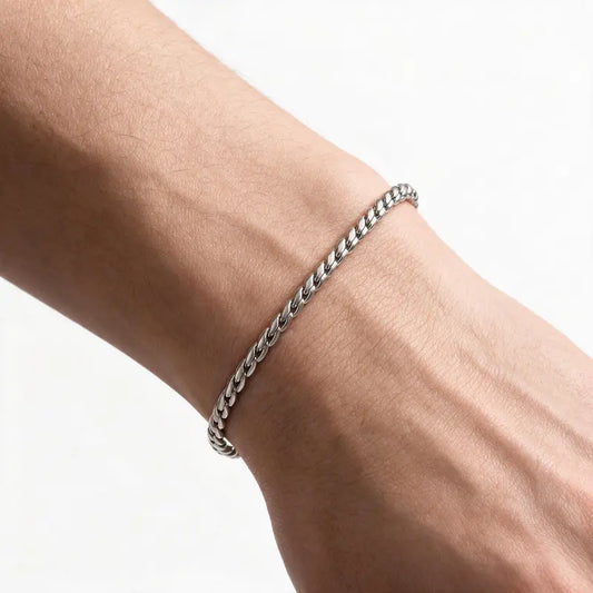 Silver stainless steel slim snake link bracelet worn on wrist, white background