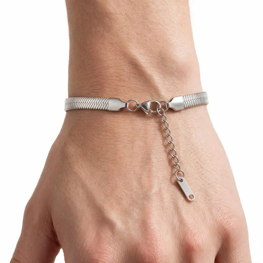 Silver stainless steel herringbone snake chain bracelet worn on wrist, white background