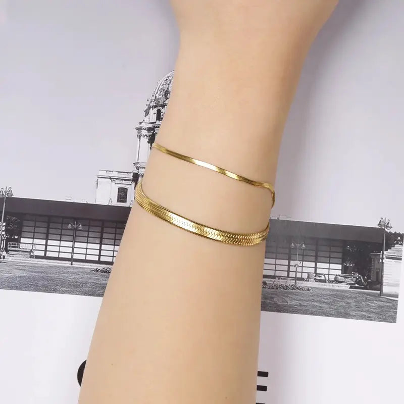 Gold snake chain bracelets stacked on wrist