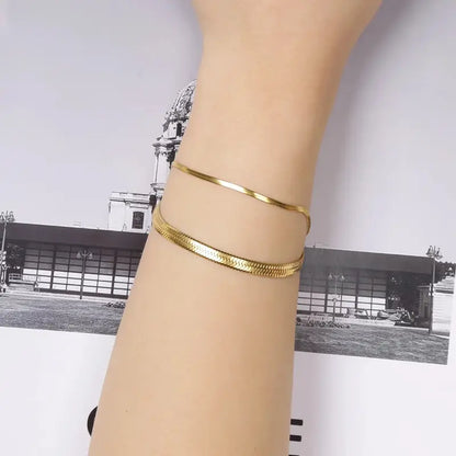 Gold snake chain bracelets stacked on wrist