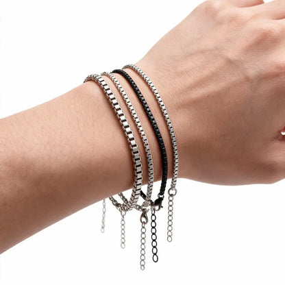 Set of 4 stainless steel box chain bracelets worn on wrist, white background