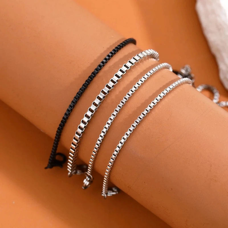 Close-up of stacked silver and black box chain bracelets on wrist